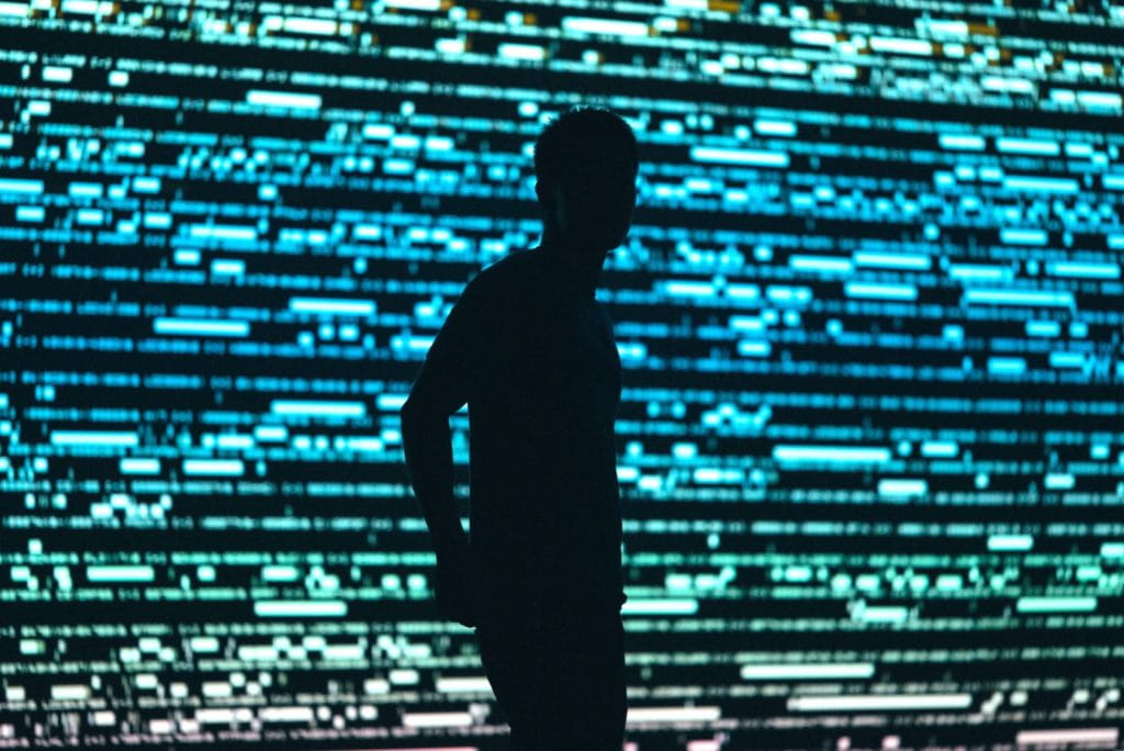 a man with a huge computer screen at the back